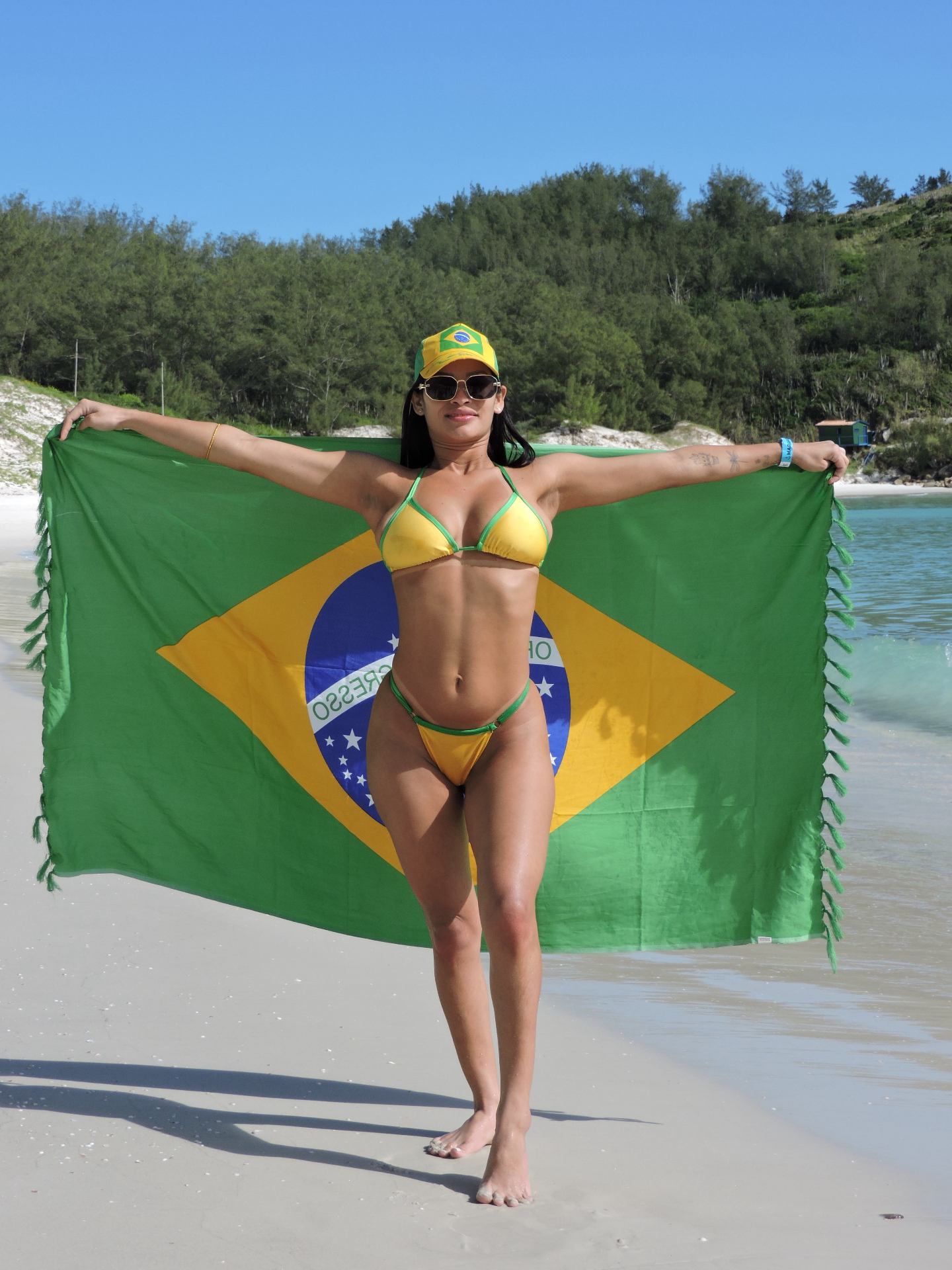 Modelo Honey segurando a bandeira do Brasil na praia
